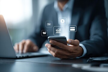 Close-up of person using smartphone with financial icons overlayed, working at laptop