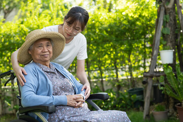 Caregiver help and care Asian senior woman patient sitting on wheelchair at nursing hospital ward,...