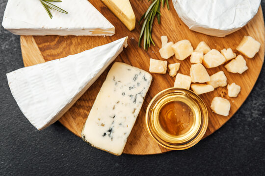 Delicious cheese platter with honey and rosemary on wooden board