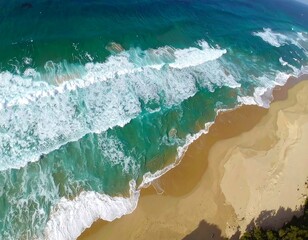 High-angle view of turquoise waves crashing on a sandy beach, showcasing the interplay of water and land.