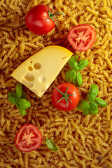 Uncooked fusilli pasta with tomatoes, basil and cheese.