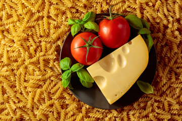 Uncooked fusilli pasta with tomatoes, basil and cheese.
