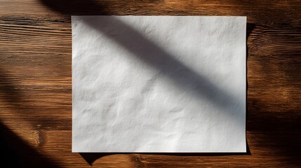 Blank paper sheet with shadow on wooden table.