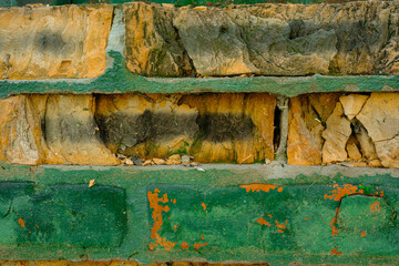 Fototapeta premium Close up of damaged brick wall with peeling green paint for weathered architecture concept