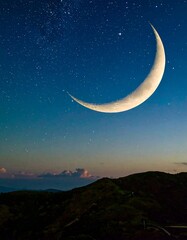 Crescent moon over a mountain range at night