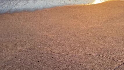 Artistic view of sand with flowing ripple patterns illuminated by warm golden light, ideal for abstract backgrounds, travel, or relaxation themes. - Powered by Adobe