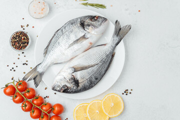Raw dorado fish with tomatoes lemon and spices on white background