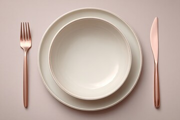 Empty, elegant, light beige plates and bowl, with rose gold cutlery on a pale pink surface