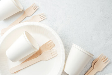 Scattered white paper cups and wooden forks on white disposable plates