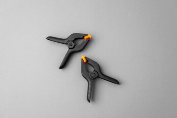 Two black clamps with orange tips on gray background