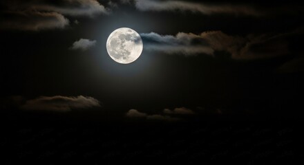 Fototapeta premium A mysterious full moon glows amidst dark clouds in night sky for captivating backdrop