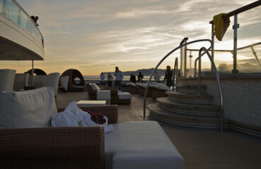 Pooldeck or swimmingpool with sun deck on modern cruiseship or cruise ship liner with elegant lounge furniture deck chairs and rattan sun beds loungers