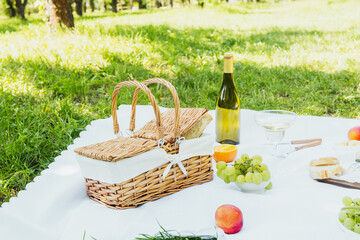Wicker basket and wine on picnic blanket in orchard for concepts of countryside lifestyle and...