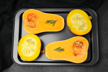 Butternut squash halves with rosemary on a baking sheet, prepared for cooking.