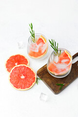 Grapefruit cocktail with rosemary and ice showing citrus slices and sparkling liquid