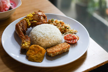 rice with fried chicken and vegetable salad (trancam) and chili sambal.