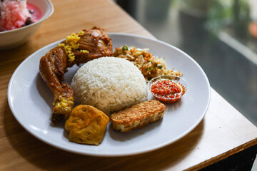 rice with fried chicken and vegetable salad (trancam) and chili sambal.