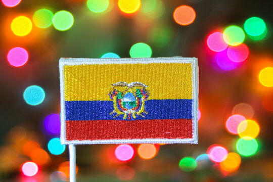 Ecuador flag embroidery with colorful bokeh background resembling fireworks, symbolizing New Year celebration, national pride and festive holiday atmosphere.