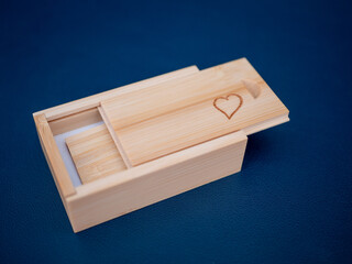 Wooden gift box with sliding lid and engraved heart symbol. Eco-friendly packaging for USB flash drive, perfect as personalized present or wedding memory storage.
