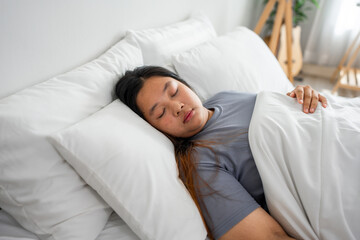 Asian plus-size woman in pajamas sleeping in the morning with happiness.