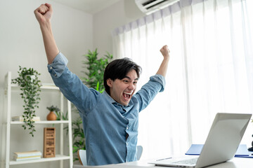 Asian excited man freelancer using laptop device working in house.