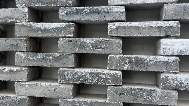 Close-up video of grey concrete blocks in staggered pattern with weathered textures and gaps.
