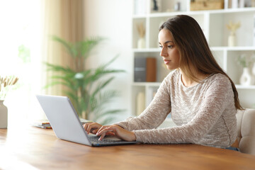 Serious woman at home using personal computer on a table