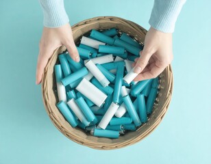 A person's hands hold a basket of batteries, highlighting recycling and environmental awareness.