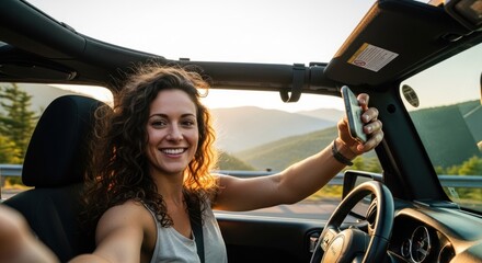 A woman in a convertible car taking a selfie with a mountainous background.