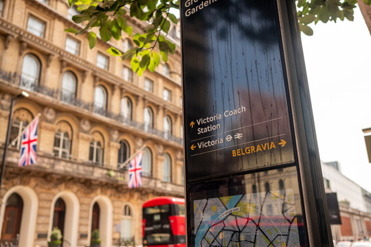 LONDON- Signage for Victoria Coach Station and Victoria railway station and Belgravia in SW1 with British flags in background - Powered by Adobe