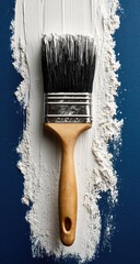 Paintbrush on a trail of white paint on a dark background