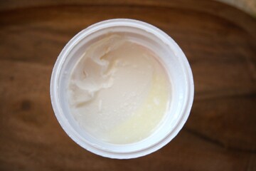 Close-up of sour cream in an open plastic container, isolated for food and dairy concepts.