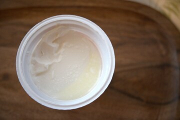 Close-up of sour cream in an open plastic container, isolated for food and dairy concepts.