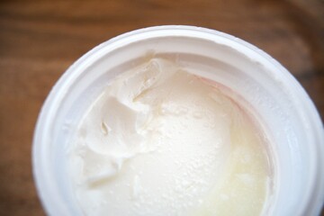 Close-up of sour cream in an open plastic container, isolated for food and dairy concepts.