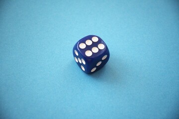 A blue die showing six dots placed on a blue background with copy space, representing luck or...