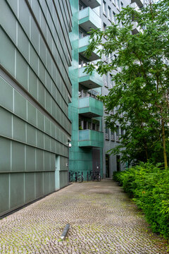 Narrow urban corridor between glass walls and vegetation, minimalist architecture integrating nature with contemporary city design, order and balance in modern development