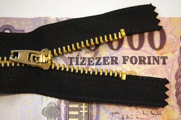 Close-up of a Hungarian 10000 forint banknote partially hidden behind a half-open zipper,...