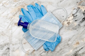 Face mask and hand sanitizer bottle on desk