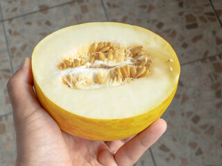 Chef showing half of a canary melon with visible seeds and white pulp, holding it in his hand, perfect for showcasing freshness and summer vibes