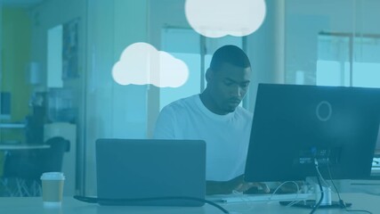 Animation of graphical clouds and computer icons over african american businessman using computer - Powered by Adobe