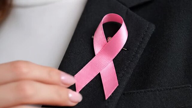 Woman holding pink ribbon for Breast Cancer Awareness Month