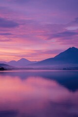 Serene sunrise over a tranquil lake reflecting vibrant pink and purple skies, with hazy mountain silhouettes