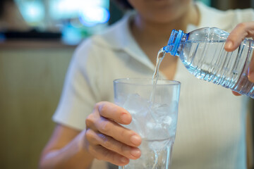Close-up of a woman pouring water from a bottle into a glass
