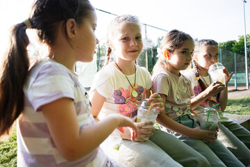 Group of young girls enjoying drinks outdoors on a sunny day