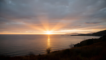 Fototapeta premium Spectacular sunset over the ocean with the sun setting behind clouds.