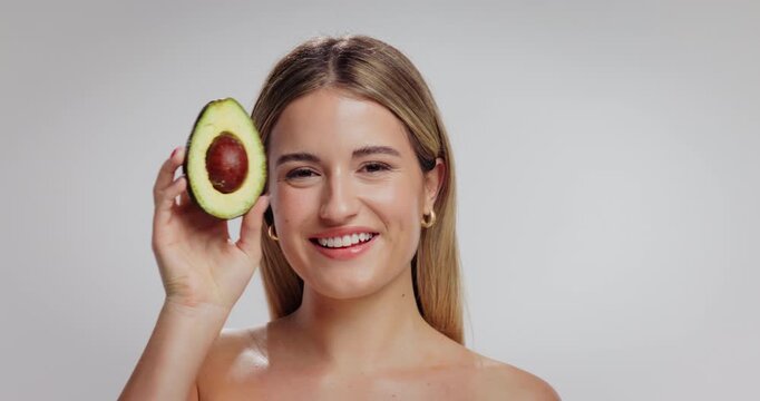 Skincare, avocado and face of woman in studio with beauty, natural and moisturizing benefits for health. Portrait, wellness and person with fruit for facial glow with dermatology by white background.