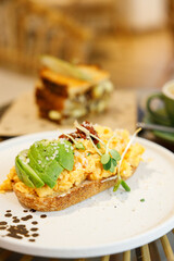Delicious healthy breakfast plate, sourdough sandwich with scrambled eggs and avocado.