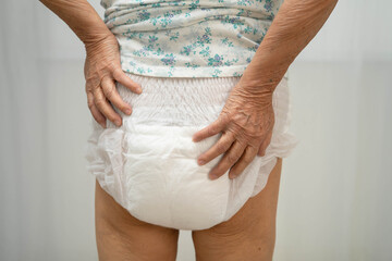Asian senior woman patient wearing adult incontinence diaper pad in hospital.