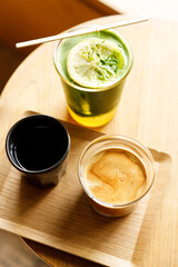 Cup of milk dirty coffee and Creation beverage of fresh matcha tea, green tea and lemon juice on wooden table by the window.