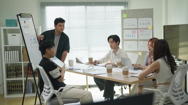 In a modern office interior, Asian business friends brainstorm a strategic growth plan. Through a hackathon and analysis, they aim to predict and summarize future business success.	